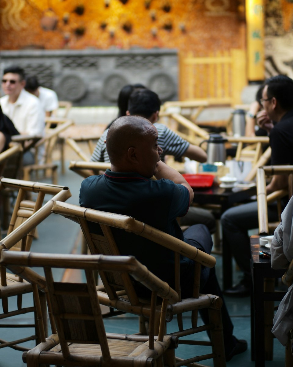 Guests sharing time in a traditional Chengdu teahouse filled with bamboo chairs