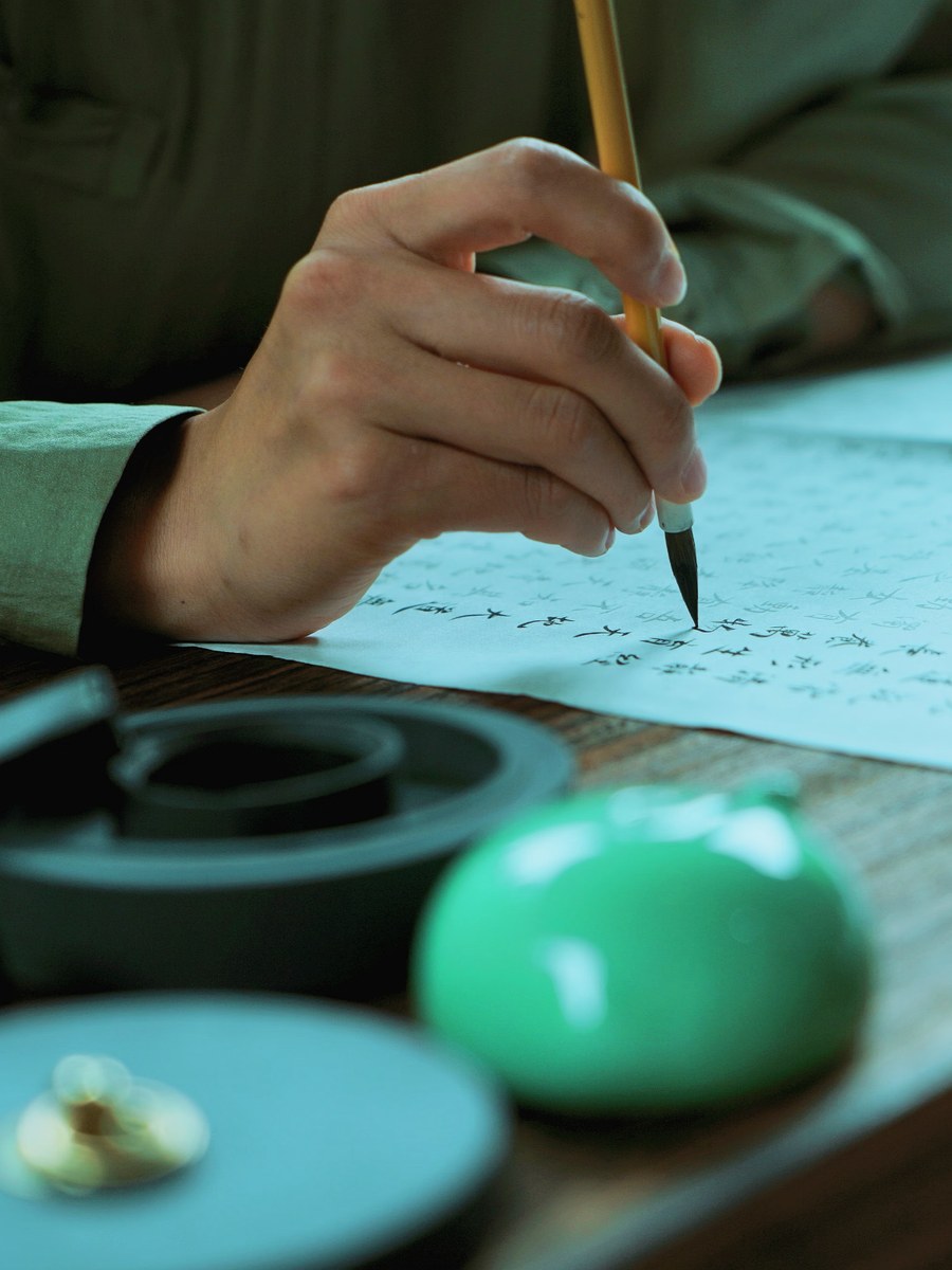 A hand using a brush to copy Chinese characters during a quiet cultural practice