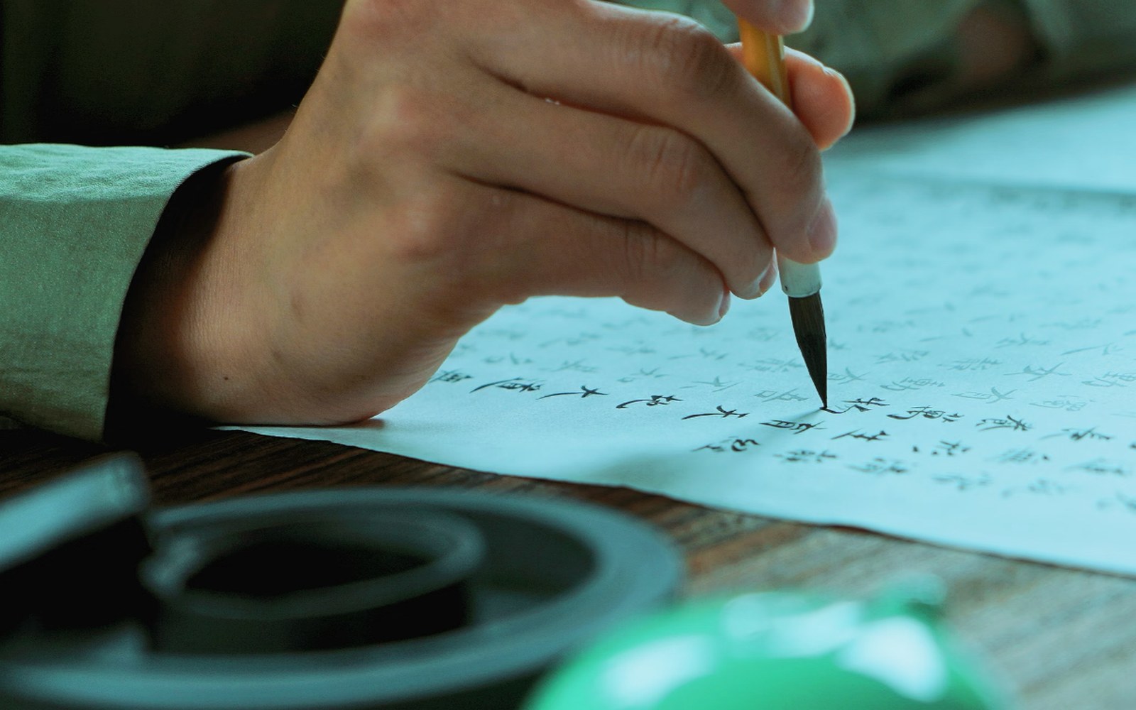 A hand using a brush to copy Chinese characters during a quiet cultural practice
